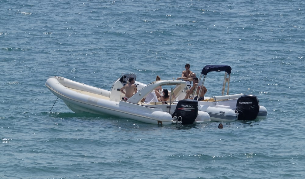 Image shows a group of people relaxing on a recreational boat in open water, concept of boating safety and alcohol related legal violations.