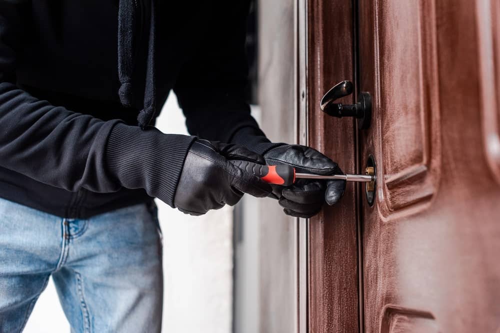 Closeup image of a person attempting to pick a door lock with tools, representing evidence involved in breaking and entering cases.