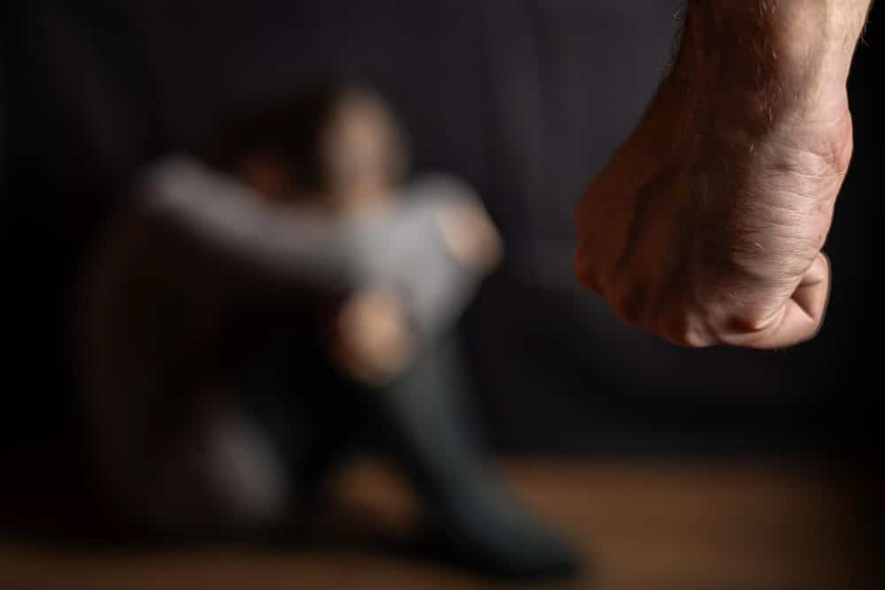 Image shows a person cowering on the floor as a raised fist approaches, concept of a domestic violence lawyer protecting victims of abuse