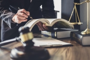 Image shows a lawyer reviewing a legal textbook at a desk with a gavel and scales of justice, concept of legal defense preparation.