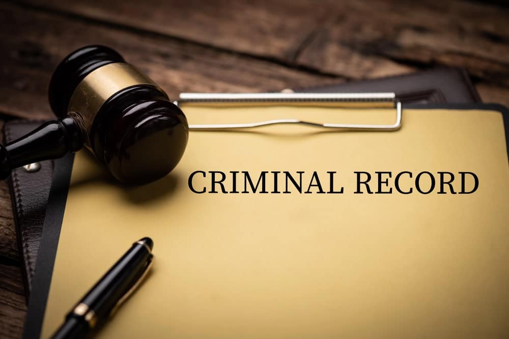 Image shows a gavel resting beside a folder labeled criminal record, representing how an expungement lawyer helps individuals clear past charges.