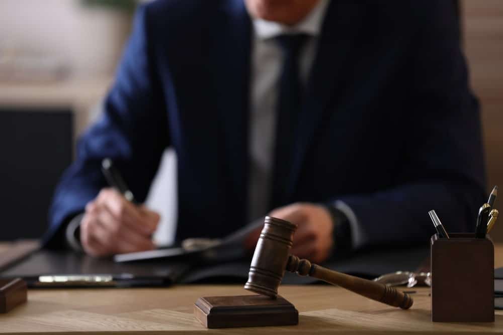 Image is of a lawyer writing at a desk with a gavel in front, concept of seizure of property lawyer providing guidance.