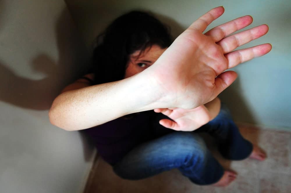 Image shows a distressed person shielding themselves with a raised hand, representing fear and vulnerability in cases handled by a statutory rape lawyer.