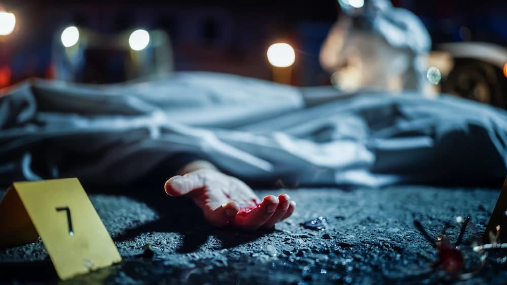 Image shows a covered body at a nighttime crash scene with evidence markers, representing how a vehicular homicide lawyer reviews forensic details in serious collision cases.