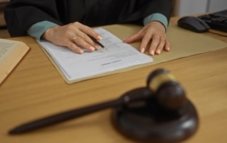 Image is of a judge reviewing legal paperwork at a desk with a gavel present, concept of Tennessee protective orders and court filing process