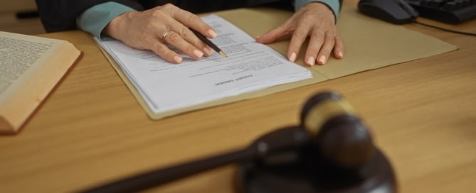 Image is of a judge reviewing legal paperwork at a desk with a gavel present, concept of Tennessee protective orders and court filing process
