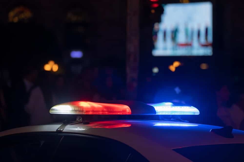 Image is of police emergency lights during a nighttime traffic stop, representing DUI license suspension actions after roadside enforcement.