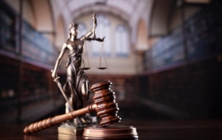 Image is of a courtroom gavel and justice statue symbolizing court proceedings and legal steps involved after a sexual assault arrest