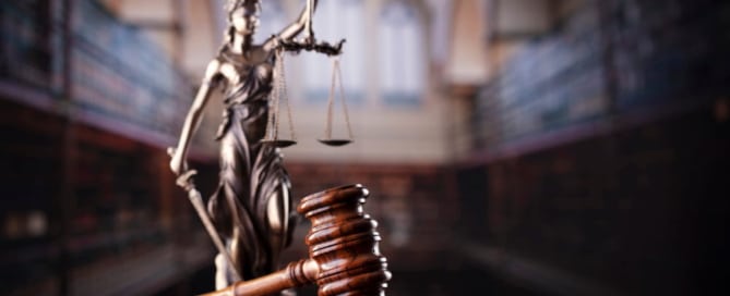 Image is of a courtroom gavel and justice statue symbolizing court proceedings and legal steps involved after a sexual assault arrest