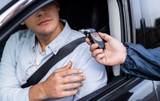 Image is of a driver being asked to take a breathalyzer during a roadside stop, concept of a breath test in Tennessee
