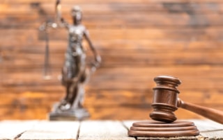Image is of a courtroom gavel with a Lady Justice statue in the background, concept of consent laws in Tennessee and how courts evaluate legal standards.