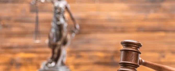 Image is of a courtroom gavel with a Lady Justice statue in the background, concept of consent laws in Tennessee and how courts evaluate legal standards.