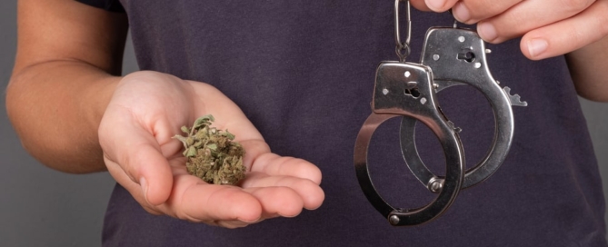Image is of a person holding marijuana in one hand and handcuffs in the other, concept of police custody after a drug arrest in Lebanon
