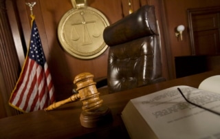 Image is of a judge's bench in a courtroom with an American flag and a gavel, concept of the judicial process for issuing no-contact orders.