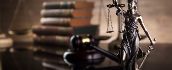 Image is of a Lady Justice statue with scales and gavel beside legal books, representing sexual assault penalties and how courts review serious criminal charges