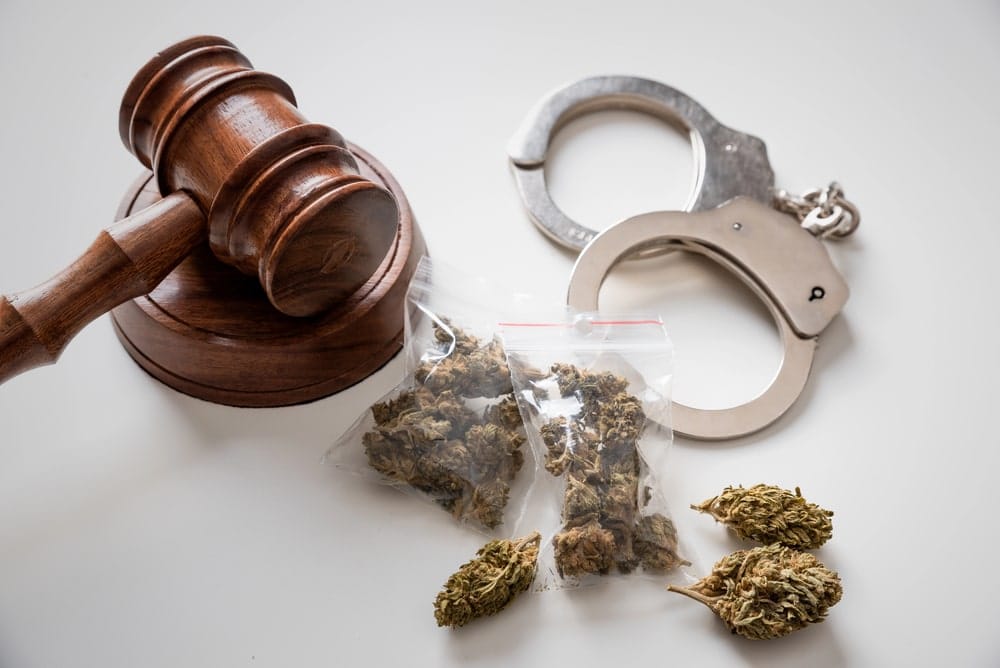 Image is of a judge’s gavel, handcuffs, and bagged marijuana on a table, representing legal consequences under marijuana laws in Lebanon