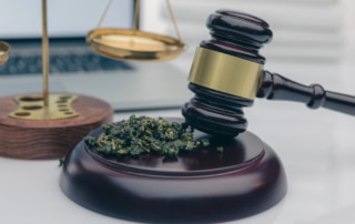 Image is of a gavel resting on a base with marijuana beside it, symbolizing court decisions related to marijuana laws in Lebanon